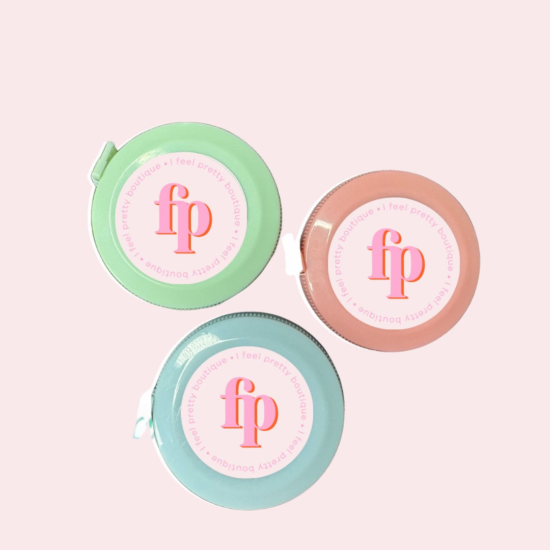 Three stylish tape measures in pastel shades, featuring the I Feel Pretty Boutique logo, designed as a fashionable accessory for plus-size women in Australia.