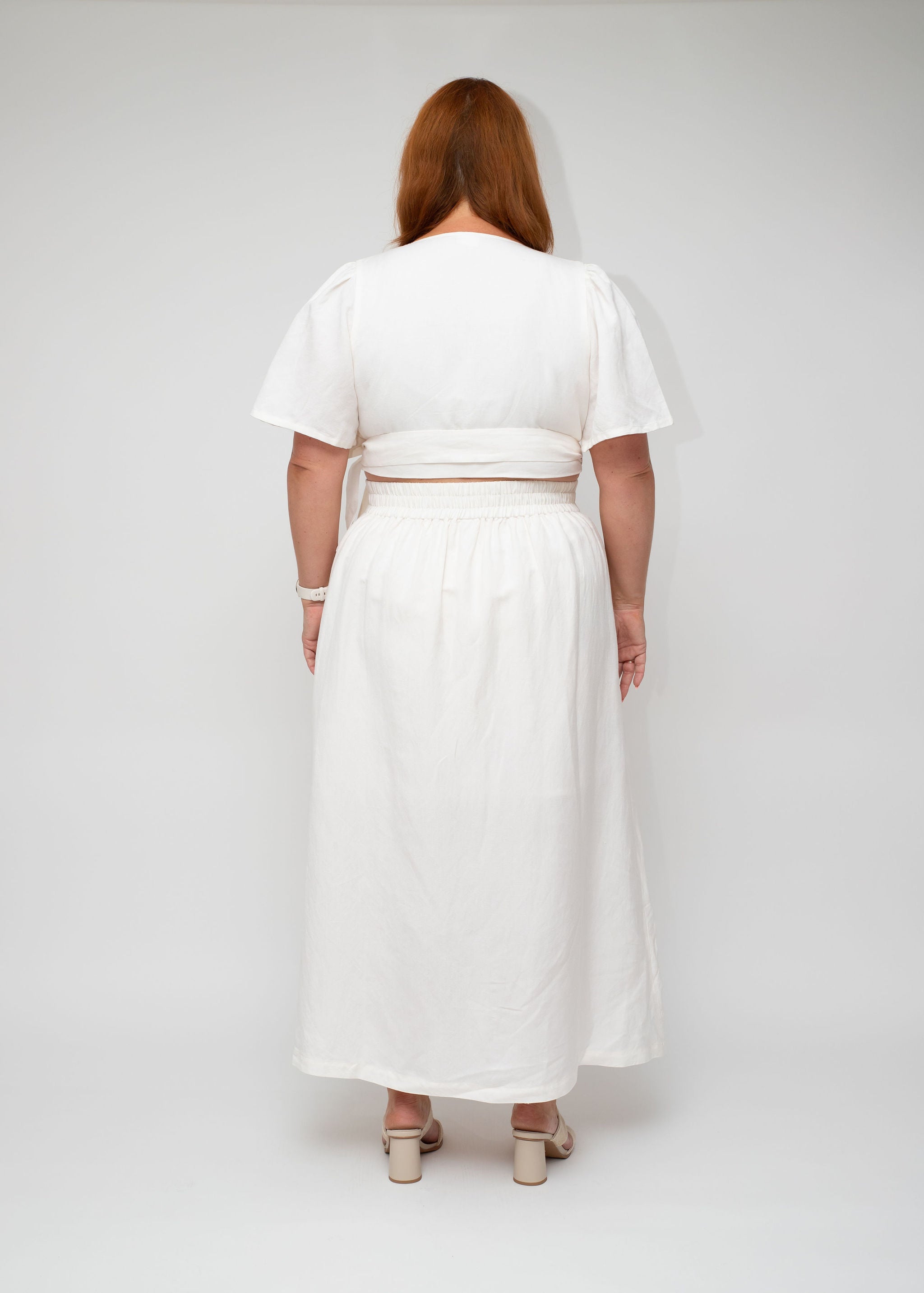 Back view of the White Linen Wrap Top and White Linen Maxi Skirt ensemble, showcasing the smooth finish and full-length flow, part of the I Feel Pretty curvy women’s collection.
